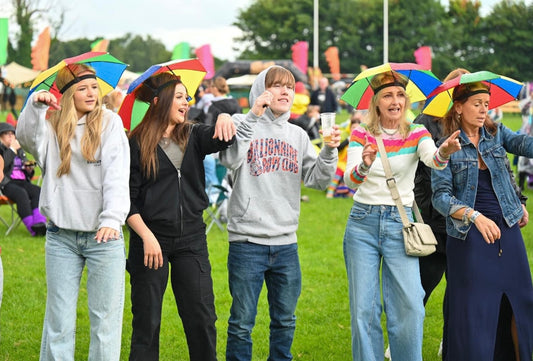 Group of people with colourful umbrella hats at a festival.