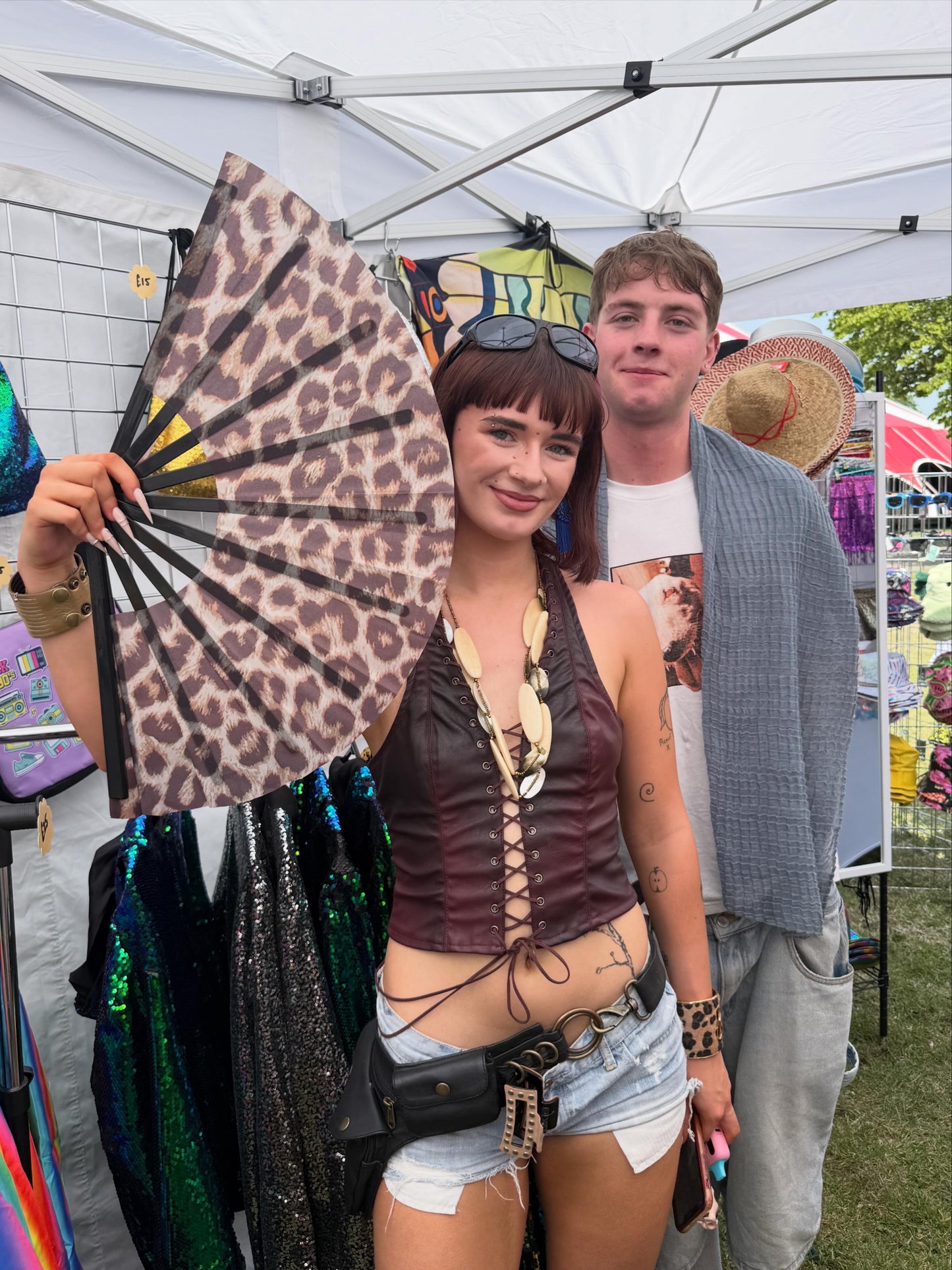 Two people at a festival with one holding a leopard print fan.