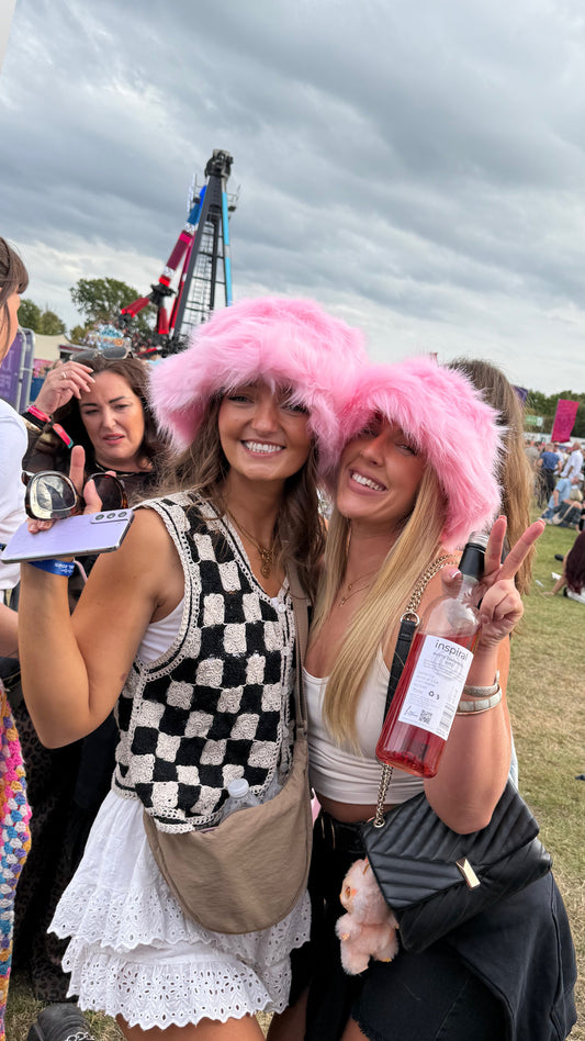 Two women with pink wigs posing together at an outdoor event.