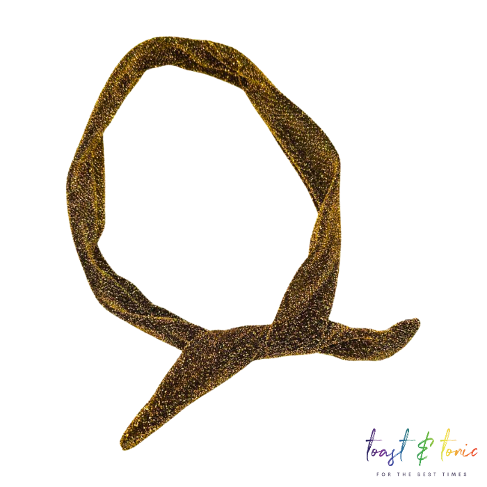 Gold glitter twist headband accessory, shimmering metallic fabric, stylish knotted design, perfect for party, festival, or holiday outfits.